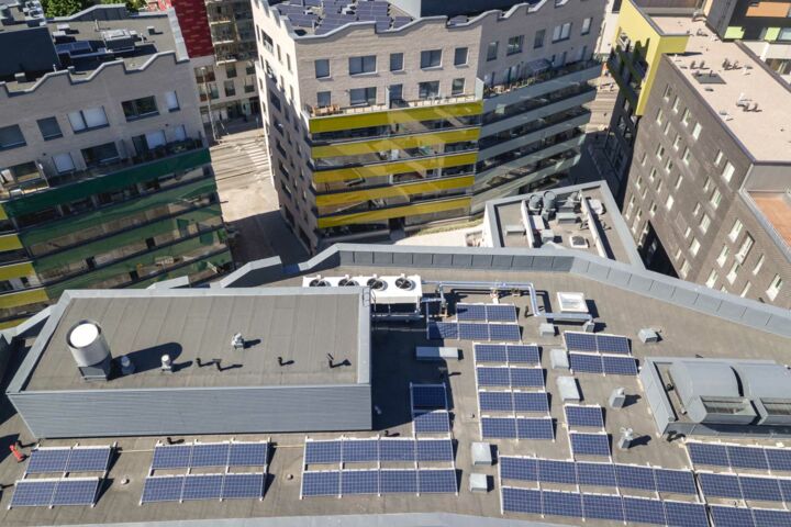 Aufsicht auf mehrere Däche mit Solarmodulen in einer dicht bebauten Stadt.